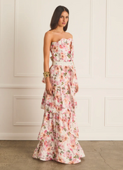 Woman wearing a floral strapless dress against a white wall.