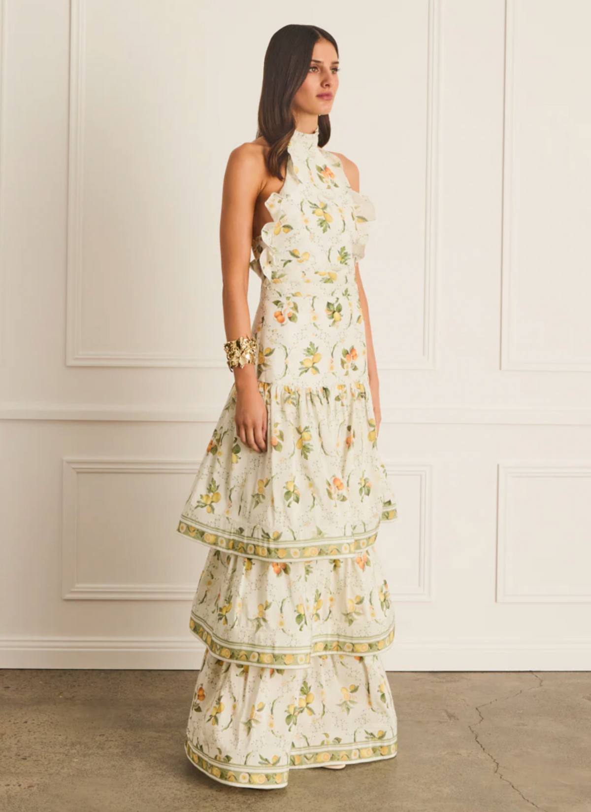 Woman wearing a floral dress against a white paneled wall.