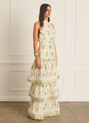 Woman wearing a floral dress against a white paneled wall.